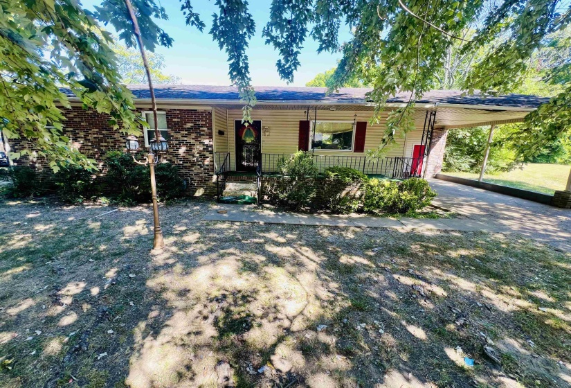 Ranch-style home featuring a porch, brick siding, a carport, and concrete driveway