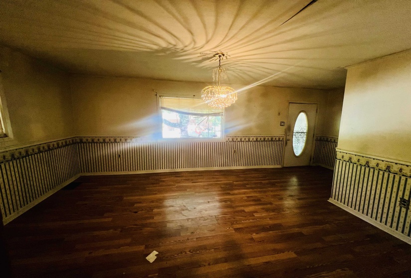 Unfurnished room with a wainscoted wall, a chandelier, and dark wood-style flooring