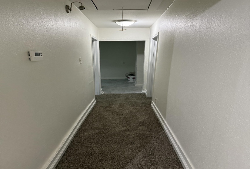 Hall with dark colored carpet and a textured wall
