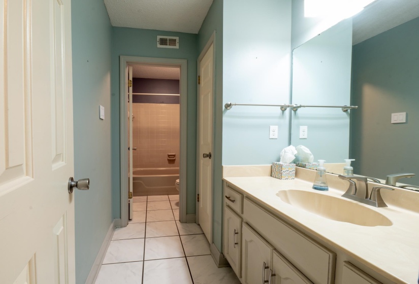 Bathroom featuring a single vanity with an integrated sink, brushed nickel faucet, and a large wall-mounted mirror