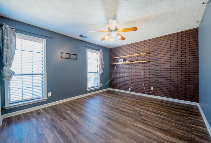 Interior room featuring wood-finish flooring and a brick-pattern accent wall