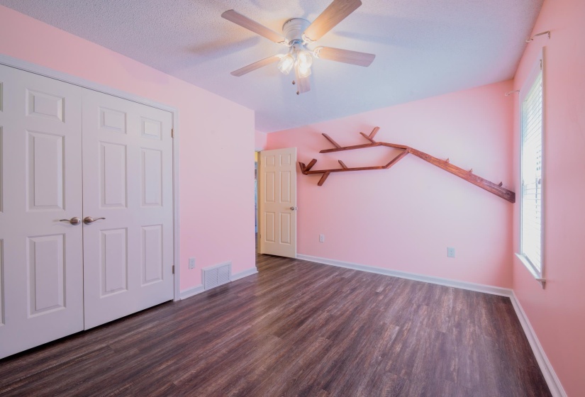 Room featuring wood-finish flooring, a ceiling fan with integrated lighting, and a window with blinds