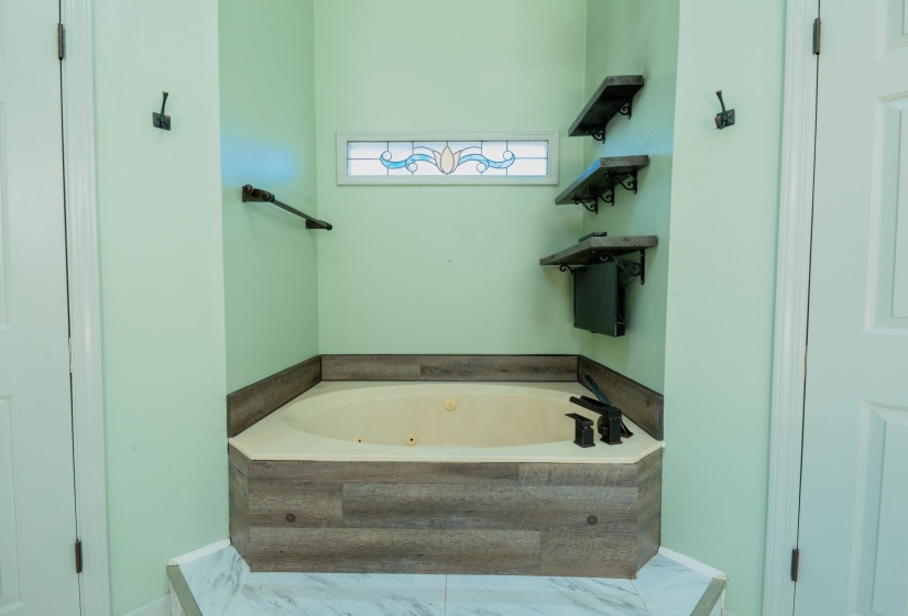 Soaking tub with integrated jets, wood-look surround, and matte black fixtures