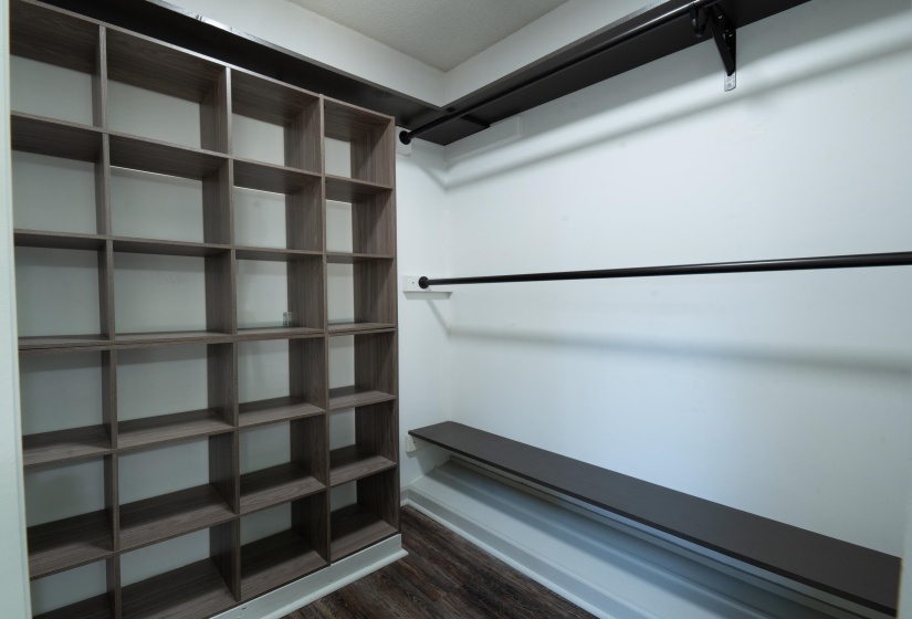 Custom closet system featuring wood-finish shelving, an integrated bench, and black hanging rods