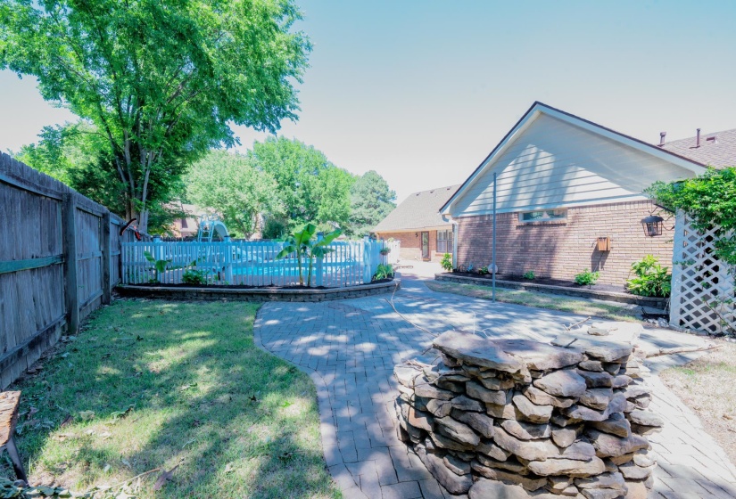 Backyard oasis featuring a swimming pool, wood privacy fence, and brick paver patio