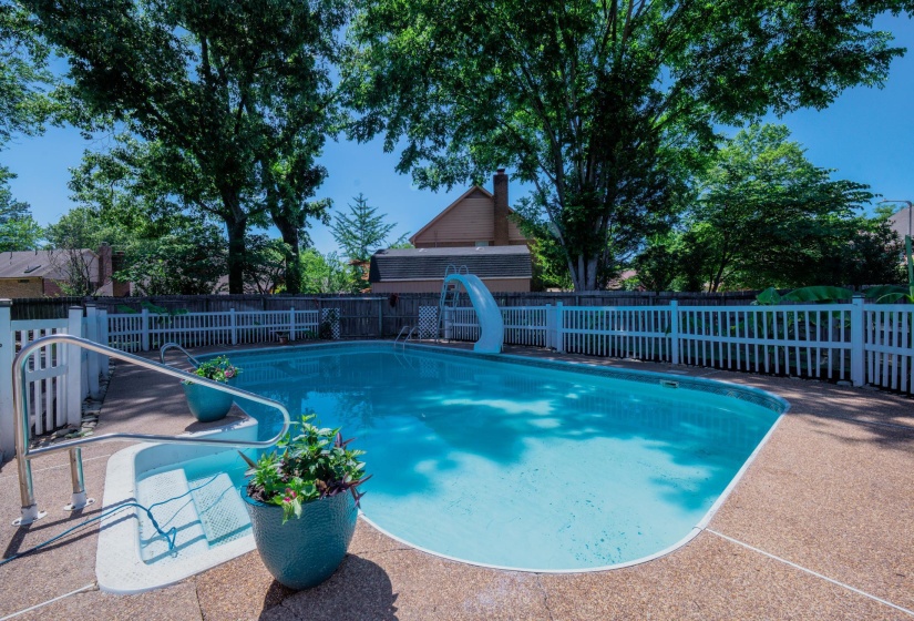 In-ground swimming pool featuring a white slide and integrated steps