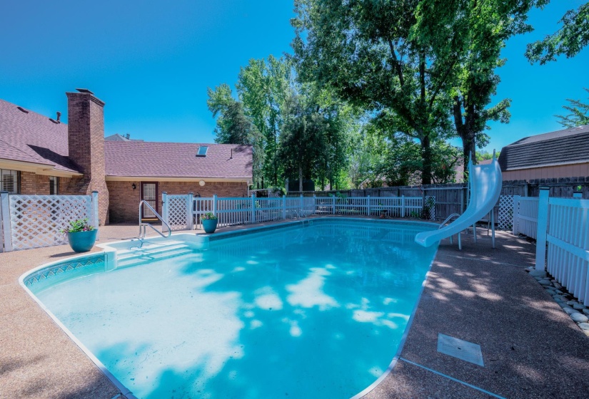 In-ground swimming pool featuring an integrated slide and entry steps