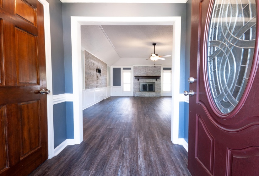 Entryway featuring dark wood-finish flooring, a vaulted ceiling, and a brick fireplace