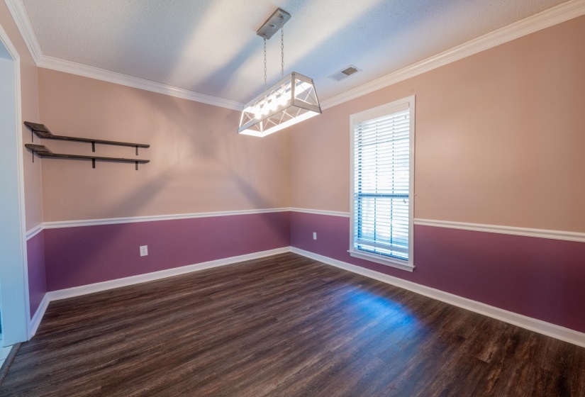 Room featuring wood-finish flooring, two-tone wall paint, a single window with blinds, and a decorative overhead light fixture