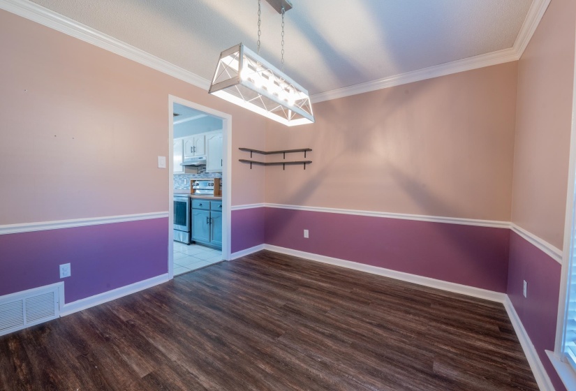 Room featuring wood-finish flooring, two-tone painted walls with chair rail molding, and crown molding