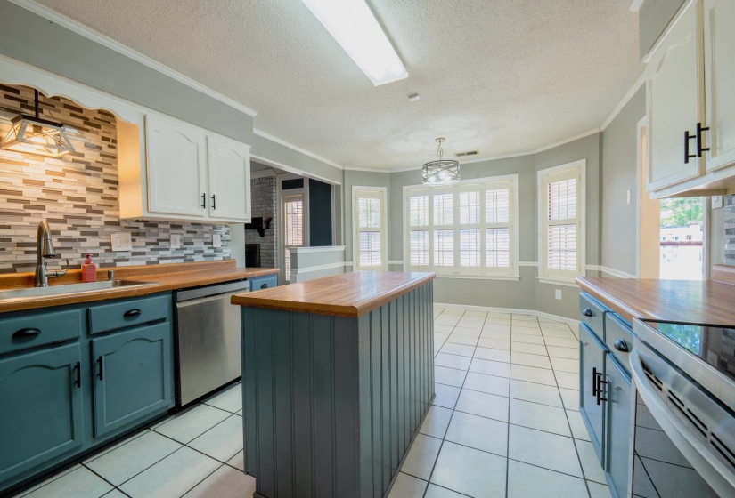 Kitchen featuring a central island, wood-finish countertops, and a tiled backsplash