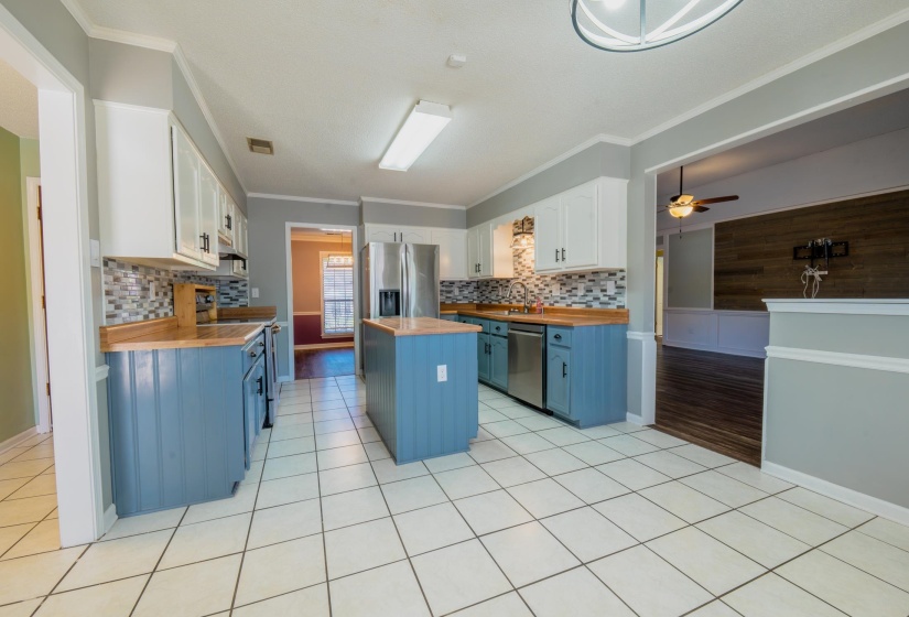 Spacious kitchen featuring white upper cabinetry, blue lower cabinetry, wood-finish countertops, and a patterned tile backsplash