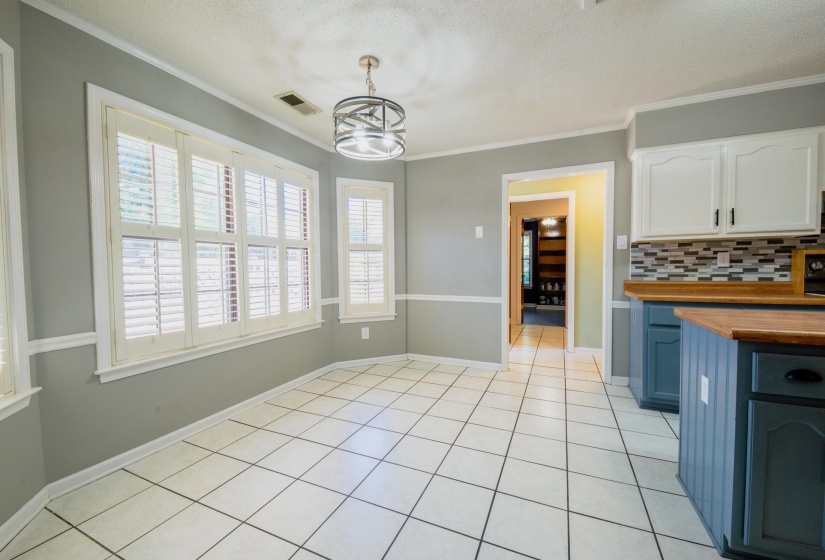 Bright breakfast nook featuring white tile flooring and a bay window with plantation shutters