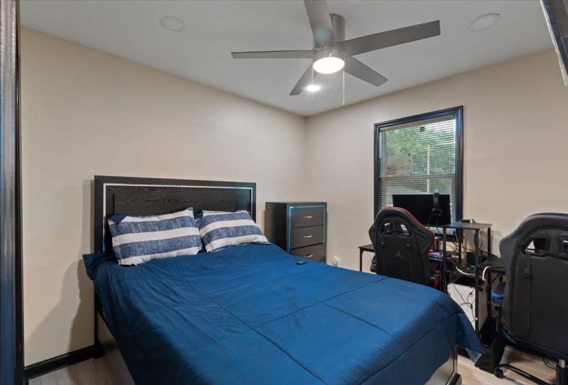 Bedroom featuring wood-finish flooring, a window with blinds, and a ceiling fan with integrated lighting