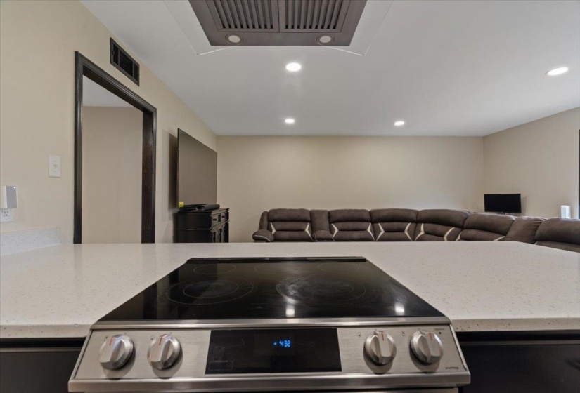 Modern induction cooktop integrated into a light-toned countertop, featuring recessed lighting and a ventilation system