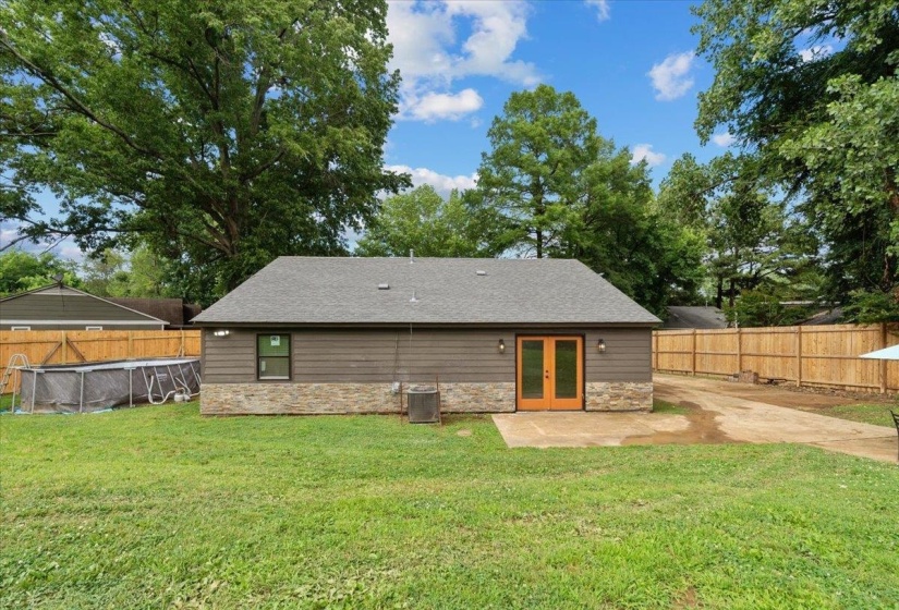 Rear exterior featuring horizontal siding, stone veneer, and a gray shingle roof