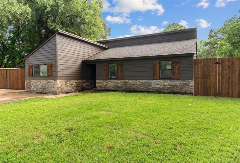 Contemporary exterior featuring horizontal siding, natural stone veneer, dark-framed windows with decorative wood shutters, and a dark shingle roof