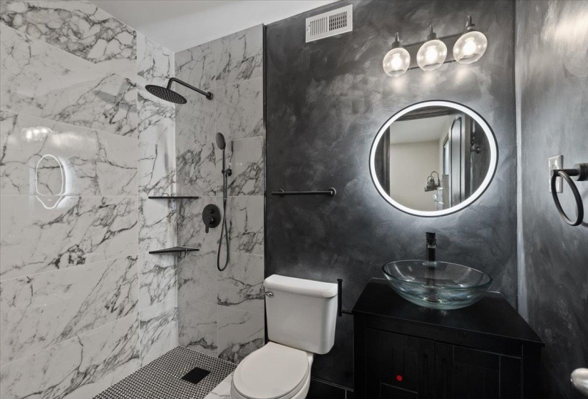 Bathroom featuring a walk-in shower with large-format marble-look tile and a black mosaic tile floor