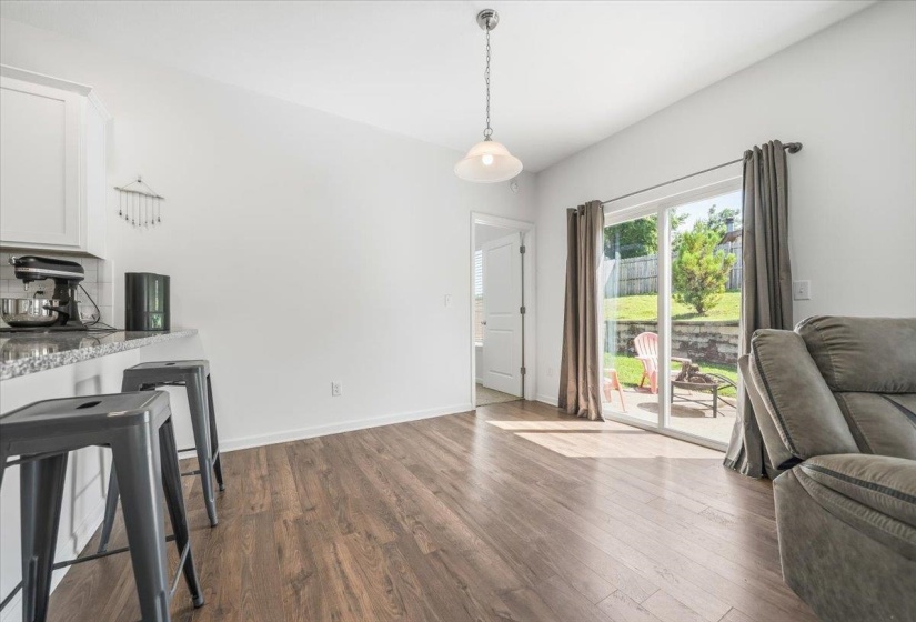 Open-concept living area featuring wood-finish flooring, white walls, and a sliding glass door to the exterior patio