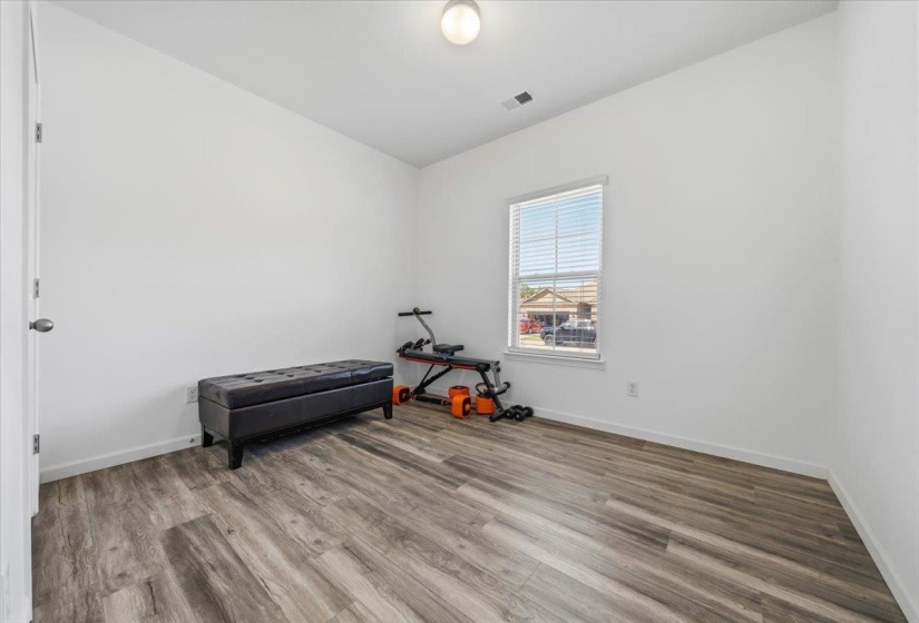 Room featuring wood-finish flooring, white baseboards, a single window with blinds, and a flush mount ceiling light