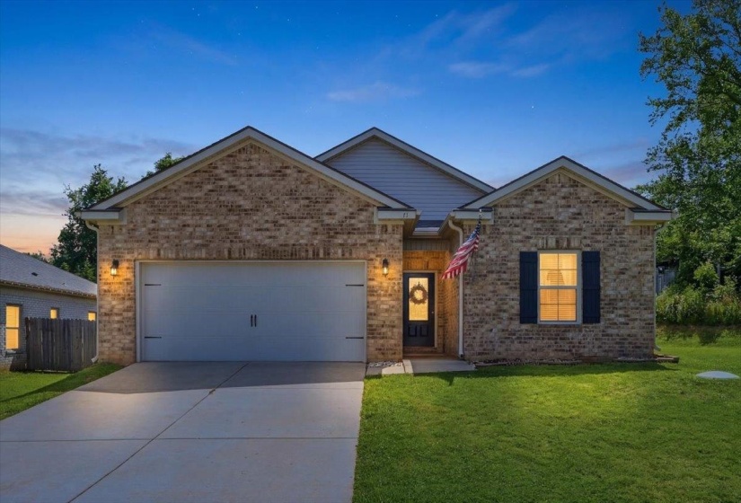 Brick facade residence featuring a two-car garage, concrete driveway, and covered entry