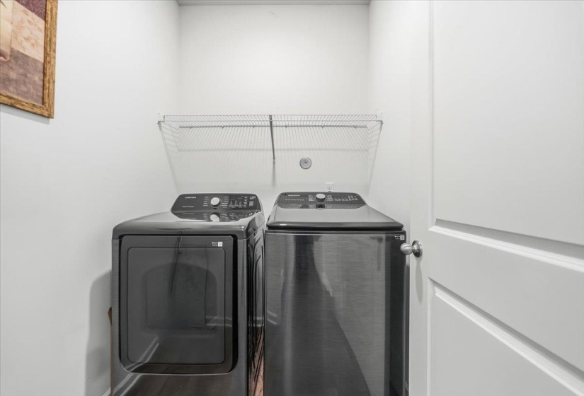 Dedicated laundry area featuring a wire rack for storage, white walls, and dark-finish appliances