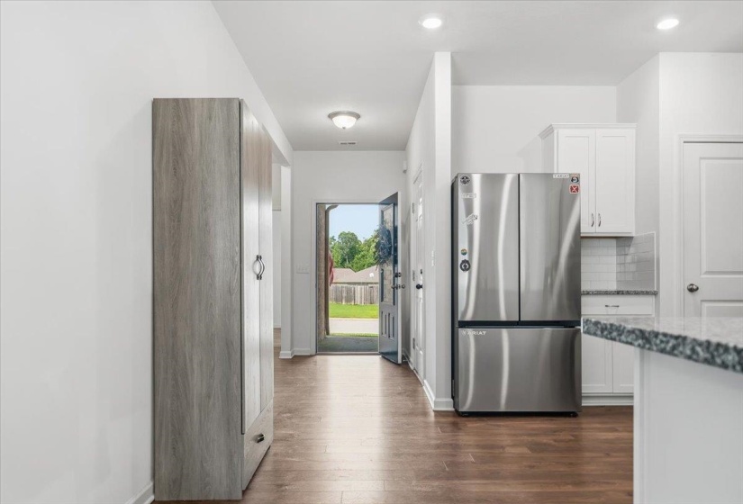 Open-concept interior featuring wood-finish flooring throughout, recessed lighting, and a stainless steel French door refrigerator