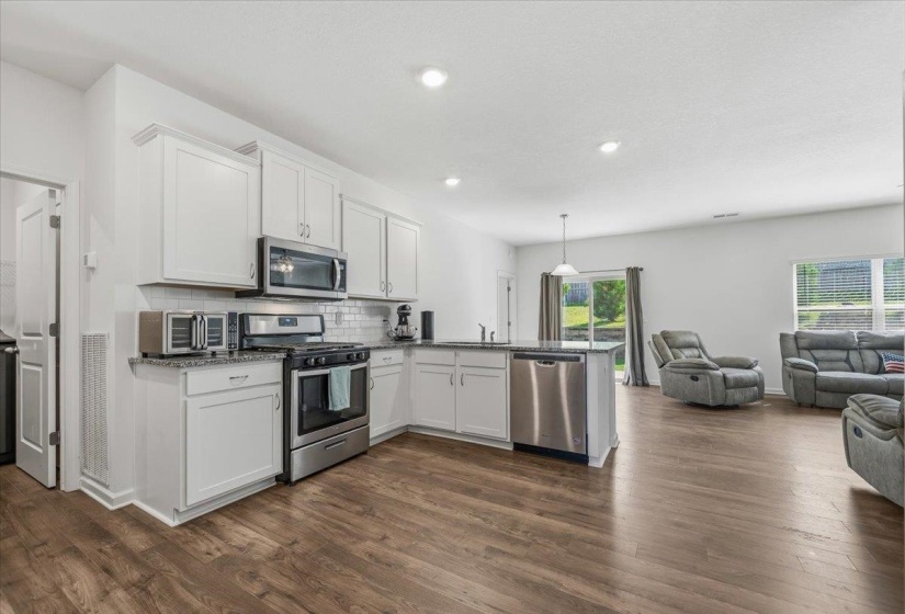 Kitchen featuring white cabinetry, stainless steel appliances, a white subway tile backsplash, and granite countertops