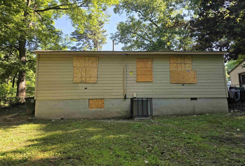 Rear facade featuring horizontal siding, a visible foundation, and mature trees providing natural canopy