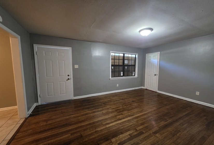 Spacious room featuring wood-finish flooring, light grey walls, and a ceiling-mounted light fixture
