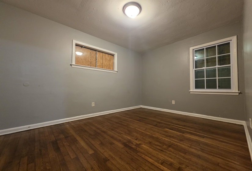 Room featuring wood-finish flooring, light gray wall paint, white baseboards, and a white framed window with multiple panes