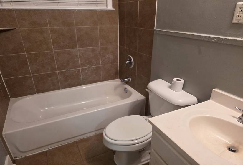Bathroom featuring a white tub, chrome fixtures, and a tiled shower surround