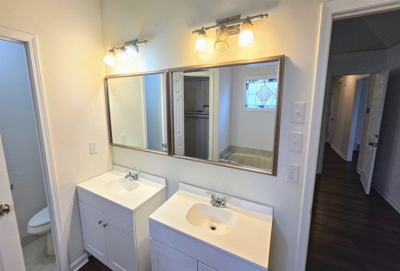Double vanity with white cabinetry and integrated sinks, brushed nickel fixtures, wall-mounted lighting, and individual framed mirrors
