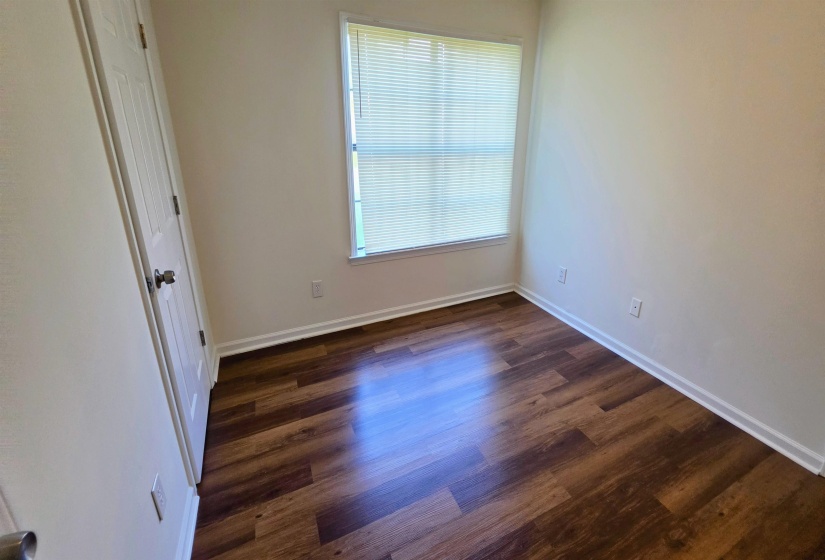 Bright interior room featuring wood-finish flooring, white baseboards, and neutral wall paint