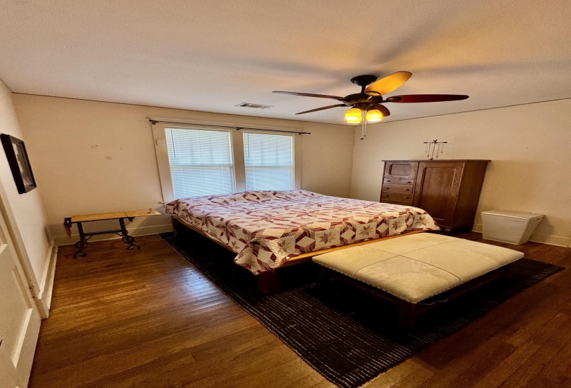 Wood-finish flooring throughout, featuring a multi-light ceiling fan, and double windows with white blinds