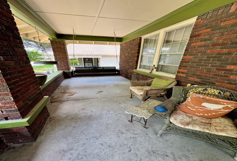 Covered front porch featuring brick columns and a concrete floor