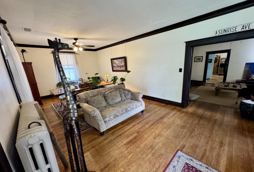 Spacious living area featuring wood-finish flooring, white walls, and dark trim