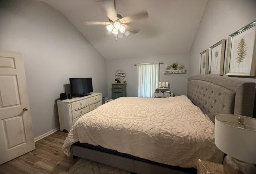 Vaulted ceiling featuring a ceiling fan, light gray wall tones, and wood-finish flooring