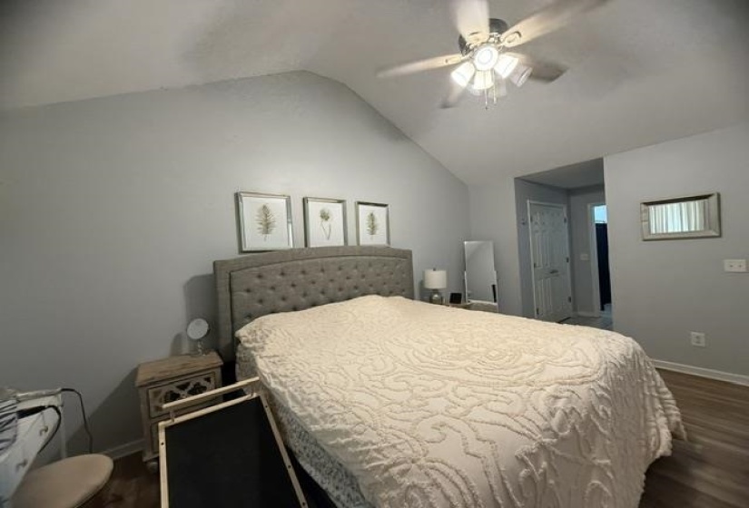 Room featuring vaulted ceiling, wood-finish flooring, and a ceiling fan with integrated lighting