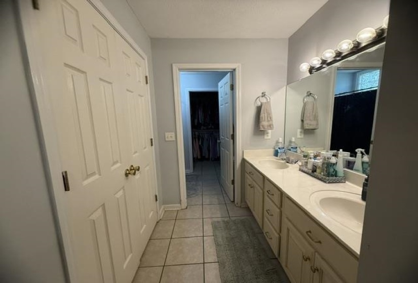 Bathroom featuring a dual vanity with integrated sinks, a large wall-mounted mirror, and tile flooring