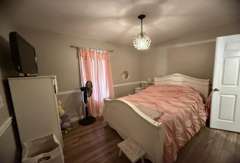 Bedroom featuring wood-finish flooring, a decorative ceiling light fixture, and a white interior door