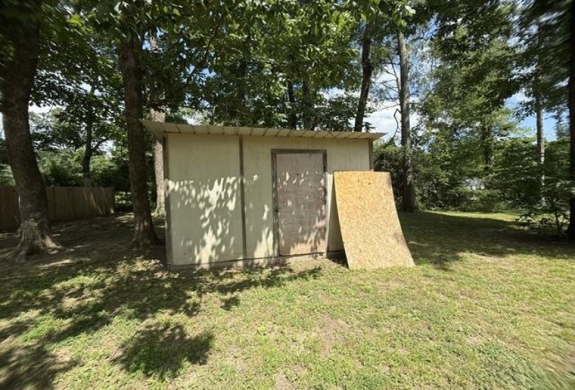 Utility shed with a single door, surrounded by mature trees