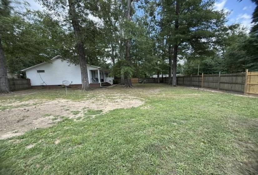 Spacious backyard featuring a mix of mature trees and open lawn space