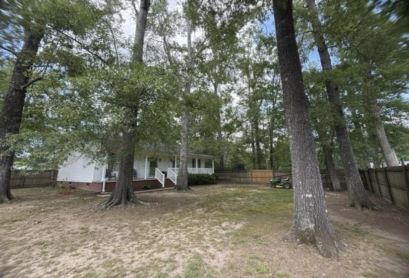 Spacious rear yard with mature trees and a privacy fence