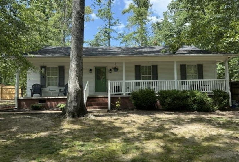 White siding exterior with a full-width covered front porch featuring white railings and dark shutters