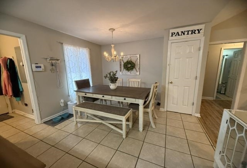 Dining area featuring neutral wall paint, a multi-light chandelier, a white six-panel door, and square tile flooring