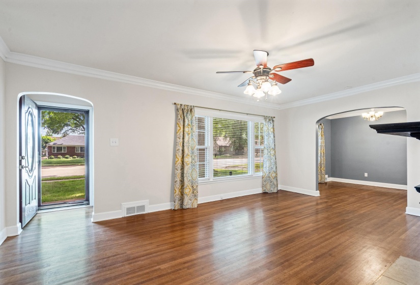 Spacious living room 20x13 featuring arched entryway, hardwood floors, crown molding, and smooth ceiling.