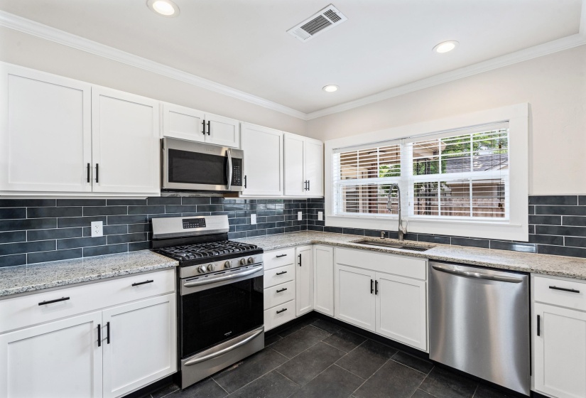 Enjoy all of the counter space accented by the beautiful tile backsplash.  You will love cooking on the gas stove. Look into the backyard with large windows over the deep sink and new dishwasher.