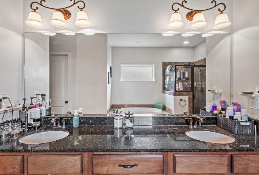 Bathroom featuring a dual vanity with undermount sinks, a dark speckled countertop, and wood-finish cabinetry