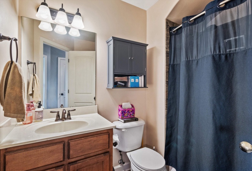 Bathroom featuring a wood-finish vanity with a white countertop and integrated sink, bronze-finish faucet, and coordinating bronze-finish light fixture